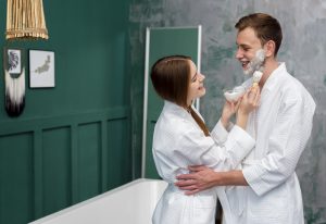 embraced smiley couple wearing bathrobes with shaving foam 1